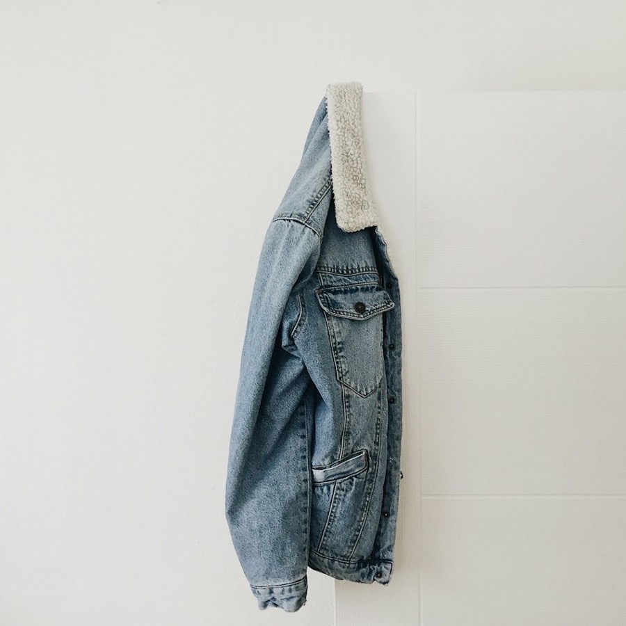 Campera de jean celeste con cuello de corderito colgada de una puerta blanca