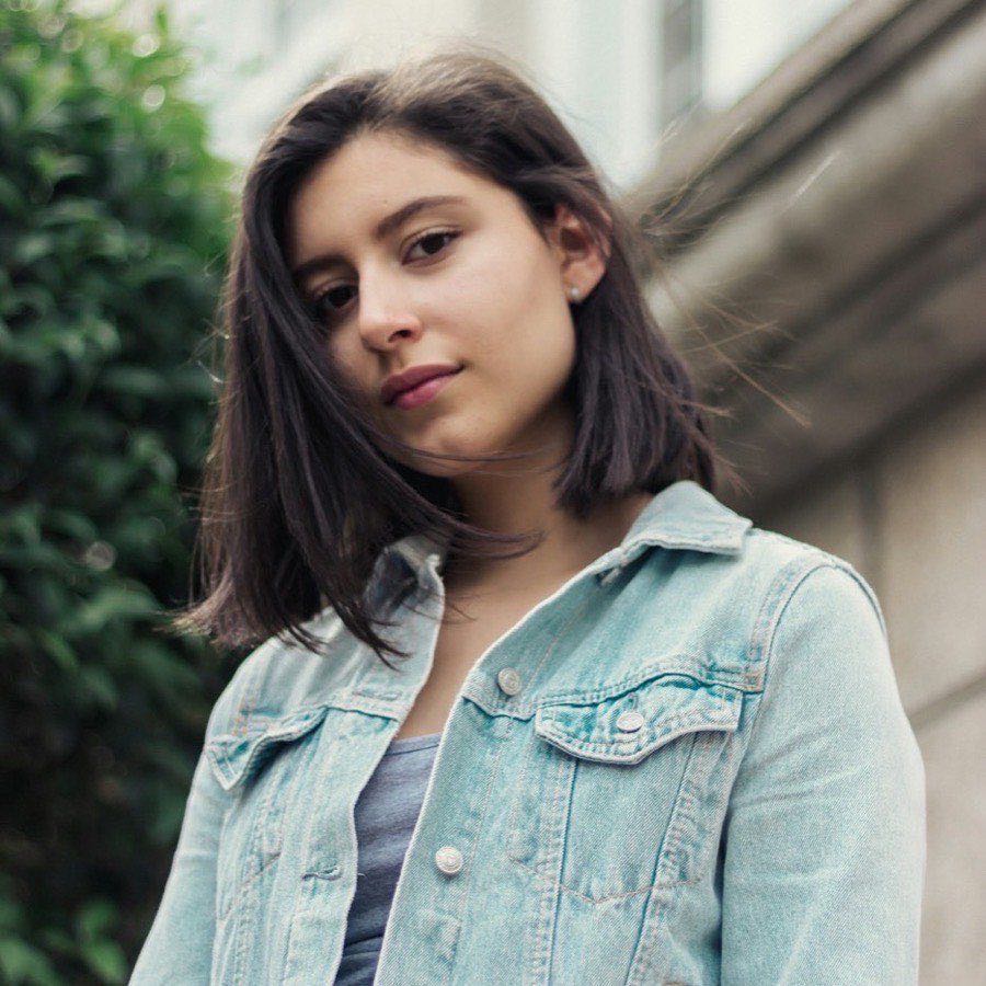 Mujer joven con una campera de jean celeste, retratada al aire libre