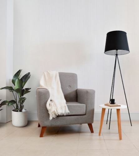 Lámpara de pie negra junto a un sillón gris
