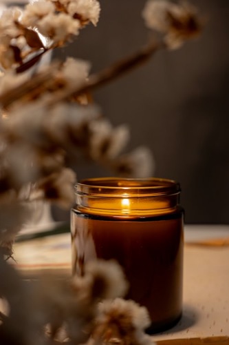 Vela aromática encendida en frasco de vidrio ámbar