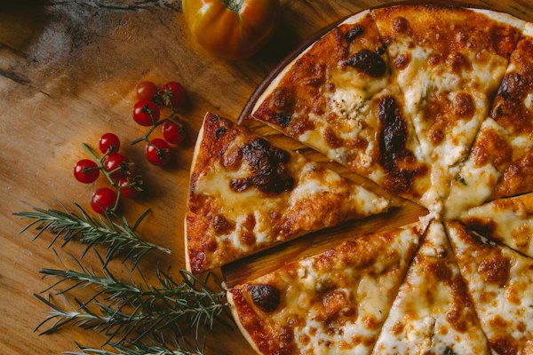 Pizza cortada en porciones con tomates cherry y romero