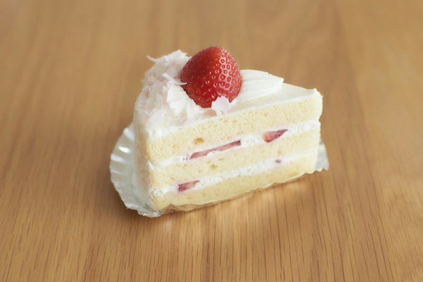 Porción de torta con crema y una frutilla