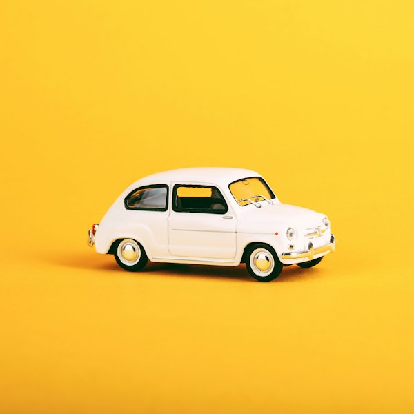 Auto de juguete blanco a escala sobre fondo amarillo