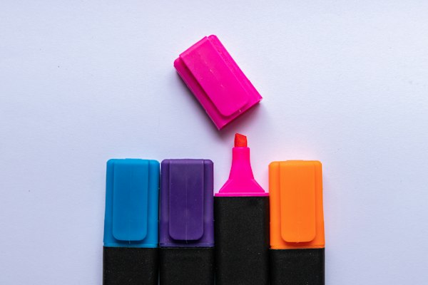 Cuatro resaltadores de colores de pie y una tapa rosa suelta