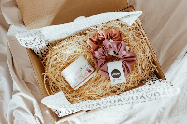 Caja de regalo con viruta, colitas para el pelo y un pote de crema