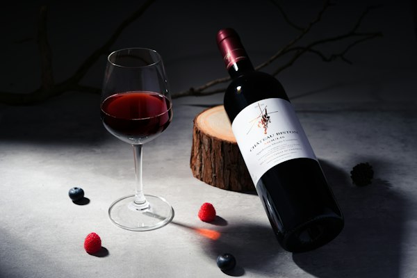 Botella de vino tinto recostada junto a una copa servida